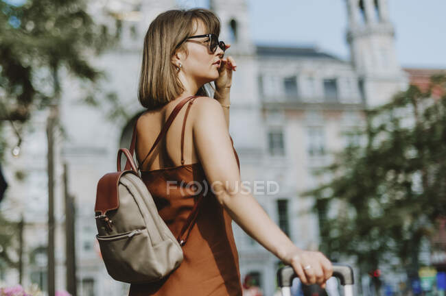 Hermosa joven con el pelo largo en gafas de sol y chaqueta posando en la calle - foto de stock