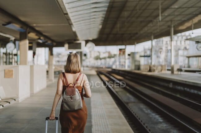 Молодая женщина с чемоданом на вокзале — стоковое фото