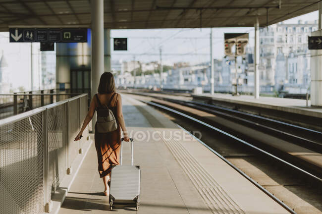 Jeune femme avec bagages et sac à dos sur la gare — Photo de stock