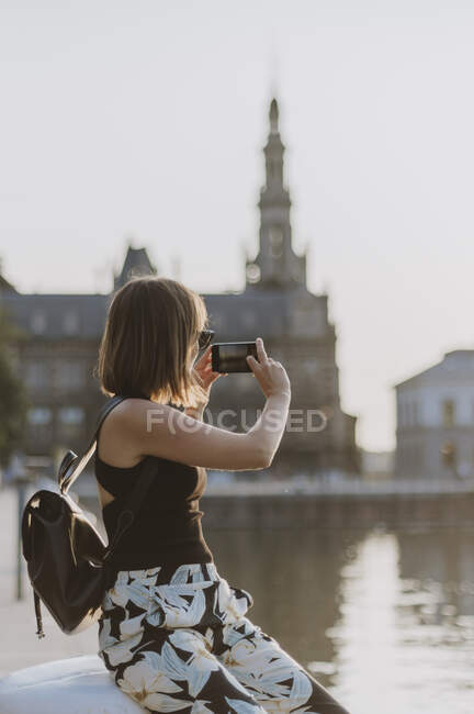 Junge Touristin mit Rucksack und Smartphone auf dem Dach der Stadt — Stockfoto
