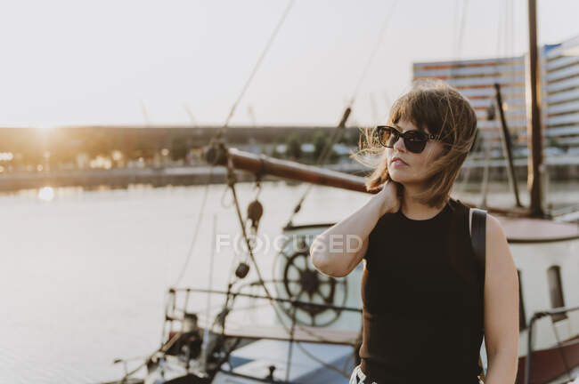 Giovane donna con i capelli lunghi in occhiali da sole in posa sul molo — Foto stock