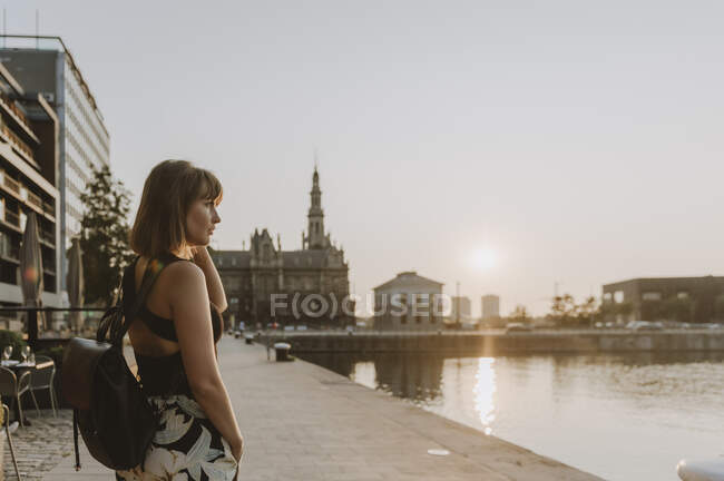 Mujer joven sentada en el puente y mirando a la distancia - foto de stock