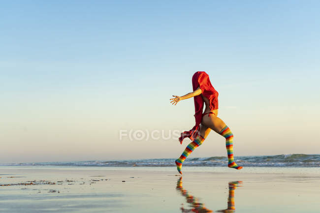 Mujer joven en calcetines de colores corriendo en la playa - foto de stock