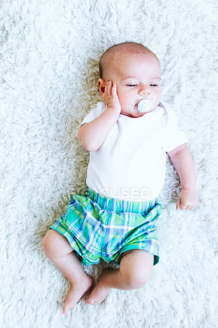 Cute baby boy with blue eyes lying on bed — Stock Photo
