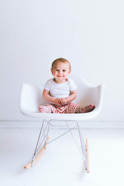 Niedliche kleine Junge sitzt auf Stuhl im Zimmer — Stockfoto