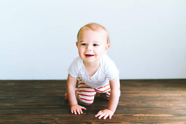 Mignon petit garçon assis sur le sol, regardant la caméra, souriant, allongé sur le tapis, — Photo de stock