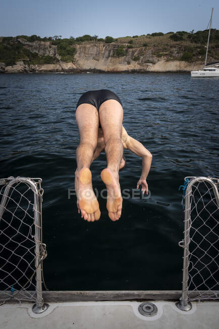 Uomo che salta dalla barca a vela nell'oceano a Rio de Janeiro, Brasile — Foto stock