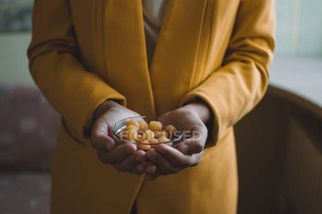Yellow raspberries in a glass plate in the hands of a girl in a yellow jacket — Stock Photo