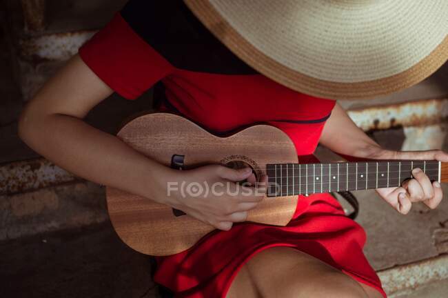 Top view of a sitting girl playing the ukulele, close-up — Stock Photo