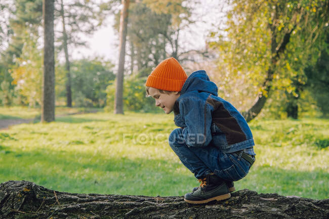 Little boy scout with spyglass during hiking in autumn forest. Child is looking through a spyglass. Concepts of adventure, scouting and hiking tourism for kids. — Stock Photo