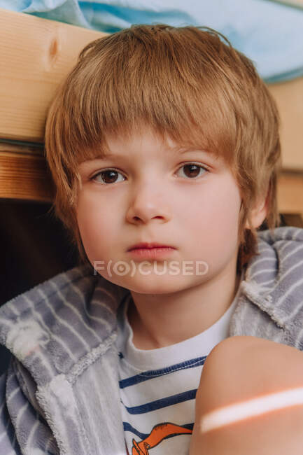 Adorable kid boy relaxing and resting after sleeping in his white bed in colorful pajama with stripes. Indoor. — Stock Photo