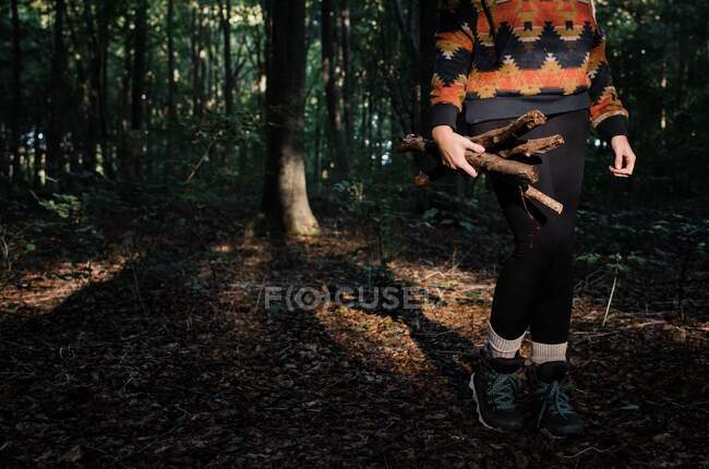 Mujer joven en un vestido negro con una espada en el bosque - foto de stock