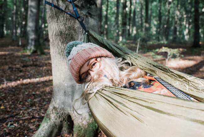 A beautiful woman is sitting in the hammock in the forest — Stock Photo