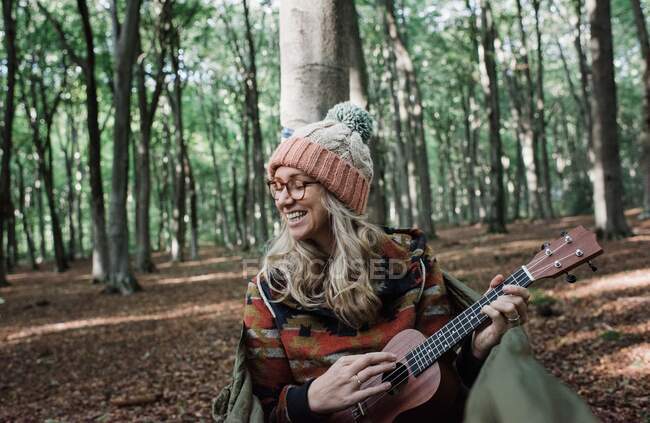 Giovane donna con chitarra nella foresta — Foto stock