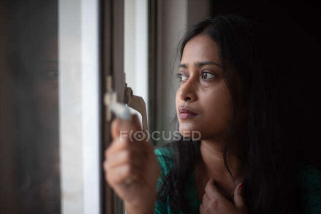 Молода жінка дивиться на вулицю через вікно — стокове фото