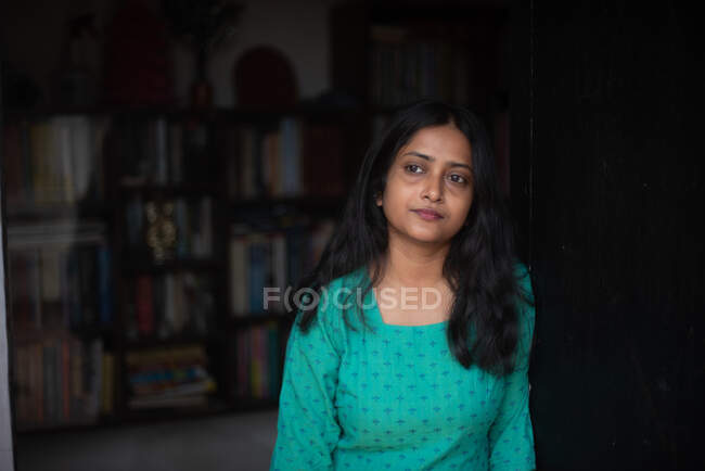 Jeune femme en robe indienne verte penchée sur la porte — Photo de stock