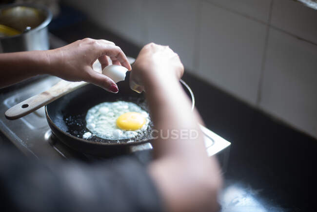 Donna che cucina uova in cucina — Foto stock