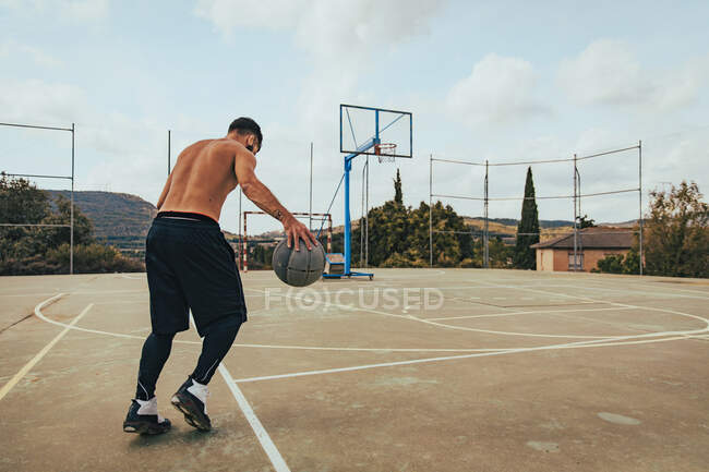 Молодий хлопчик тренується один на баскетбольному майданчику — стокове фото