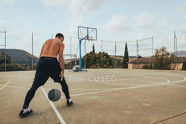 Мальчик тренируется в одиночку на баскетбольной площадке — стоковое фото