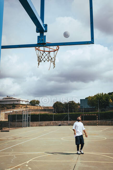 Молодий хлопець кидає баскетбол в баскетбол на дворі — стокове фото