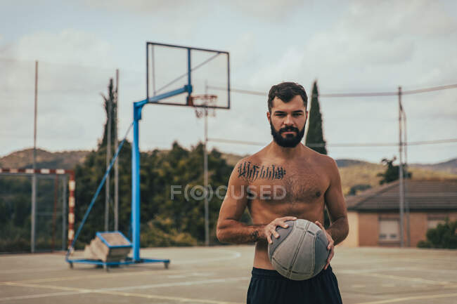 Gros plan d'un jeune garçon tenant un ballon de basket sur un terrain — Photo de stock