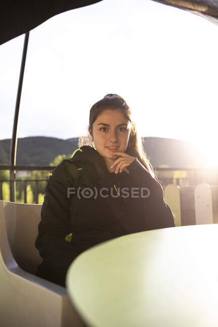 Девушка, сидящая на террасе бара, глядя в камеру — стоковое фото