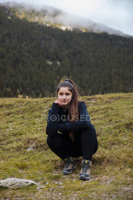 Brunette girl sitting while looking at camera in mountains — Stock Photo