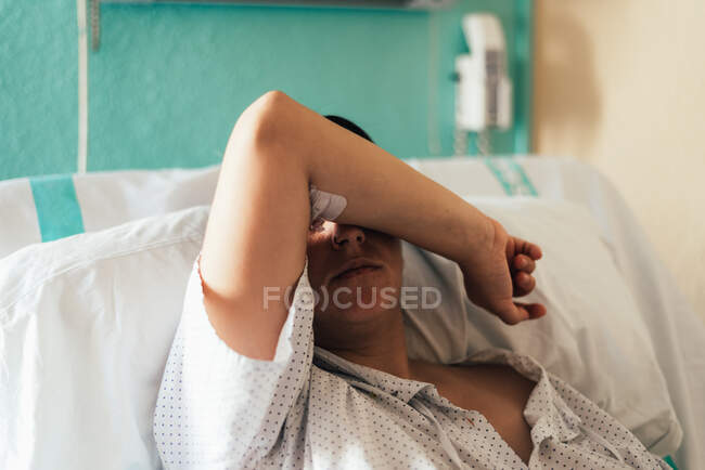 Une jeune femme hospitalisée dans un lit. geste de douleur et de préoccupation. — Photo de stock