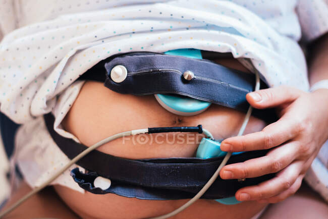 Belly of pregnant woman connected to pregnancy monitoring. Preparation to childbirth. Healthy pregnancy concept. — Stock Photo