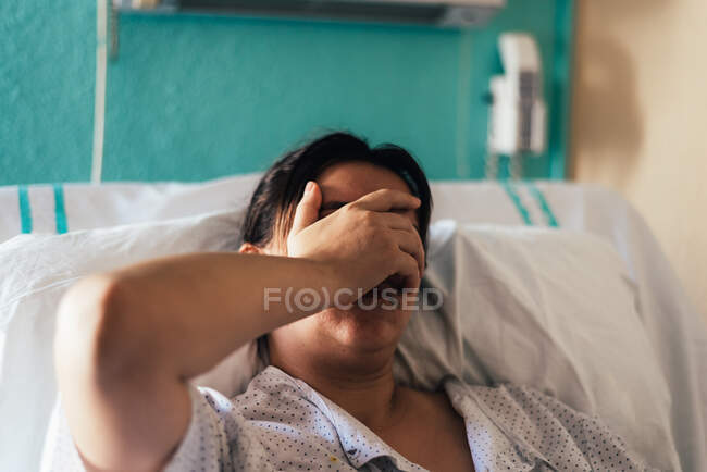 Jovem hospitalizada em uma cama. Gestos de dor e preocupação. — Fotografia de Stock