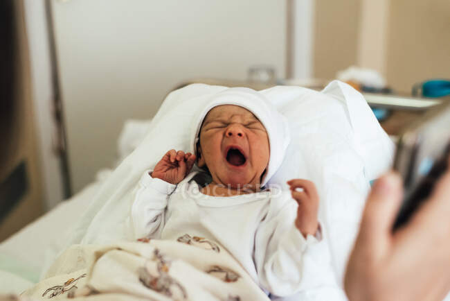 Nouveau-né pleurant dans les bras de sa mère dans un lit d'hôpital. — Photo de stock