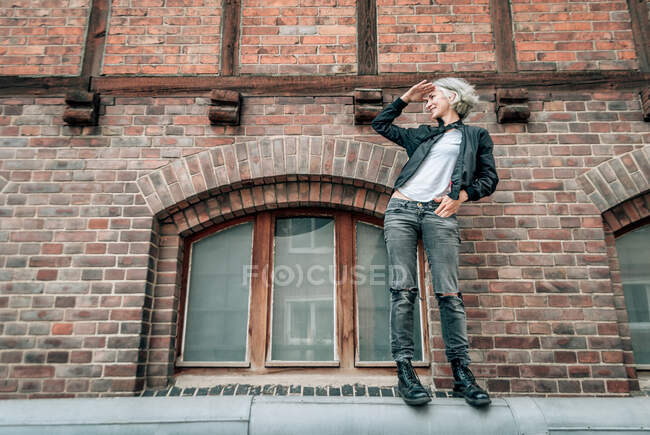 Attraktive blonde Frau in lässiger Kleidung posiert nahe Ziegelmauer — Stockfoto