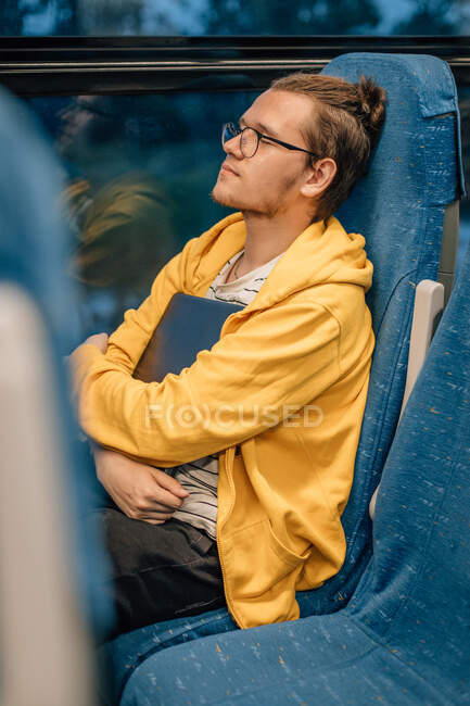 Jeune homme, adolescent, voyageant en train, embrassant un ordinateur portable. Programmeur aller au travail. — Photo de stock