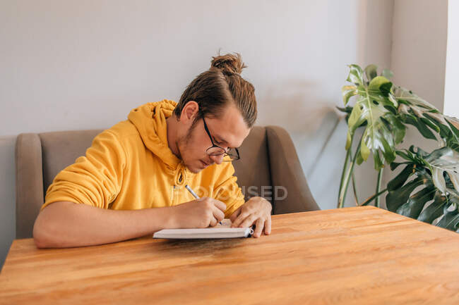 Молодий підліток пише в блокноті в кафе. Знімок стилю з простором для копіювання . — стокове фото