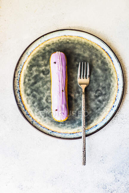 Смачний французький десертний еклер з лавандовим топінгом на тарілці — стокове фото