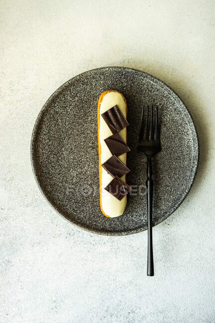 Вкусный французский десерт эклер с шоколадной начинкой на тарелке — стоковое фото