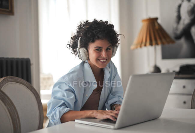 Усміхнена молода жінка працює з комп'ютером вдома — стокове фото