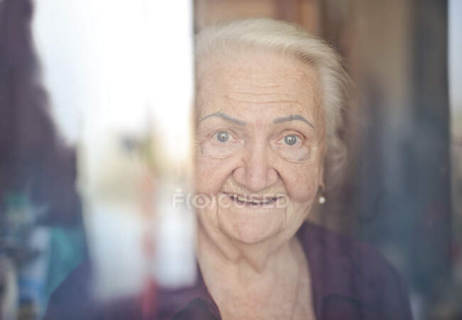 Portrait of elderly lady through the glass — Stock Photo