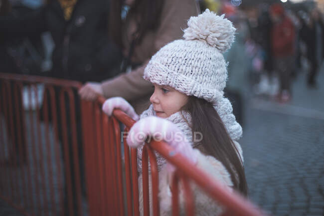 Kleines Mädchen schaut auf Karussell und wartet. Mutter im Hintergrund — Stockfoto