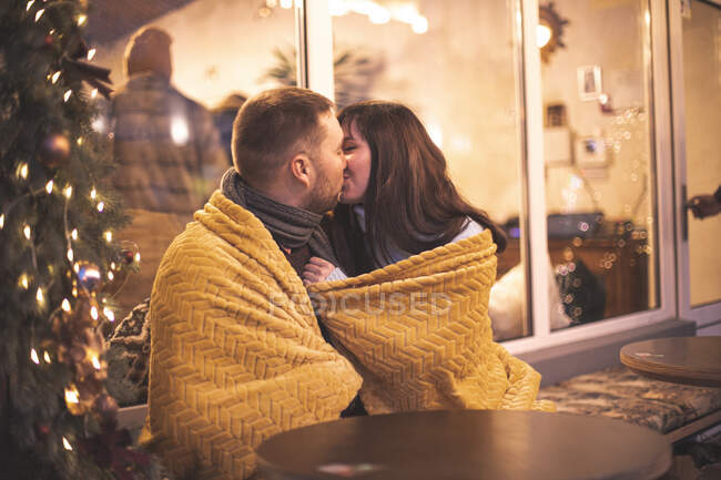 Romantic couple sitting at the sofa at the outdoor cafe during the Christmas time — Stock Photo