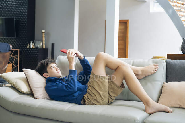 O menino jogando jogo online no smartphone em casa. — Fotografia de Stock