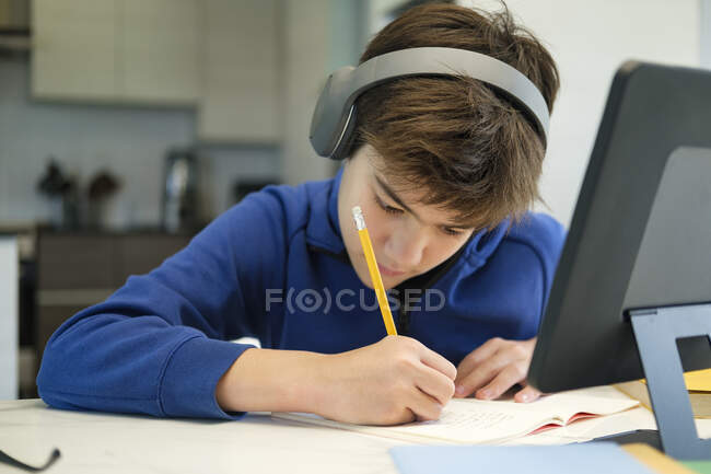 Educazione online all'apprendimento a distanza. Uno scolaro studia a casa e fa i compiti a scuola. Un apprendimento a distanza a domicilio. — Foto stock