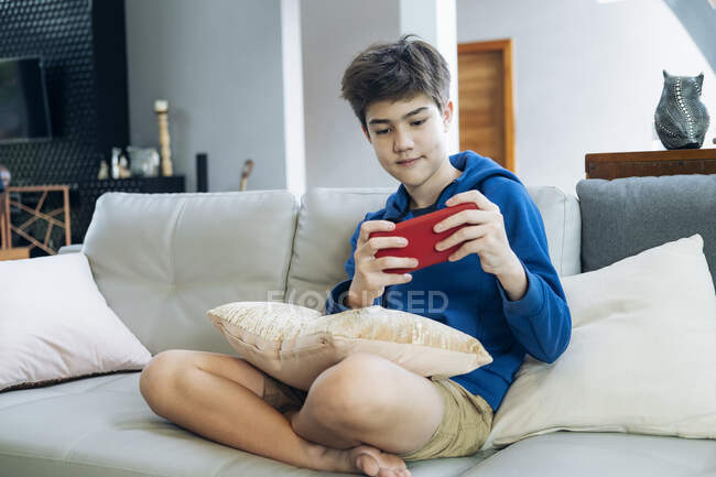 Мальчик играет в онлайн игру на смартфоне дома. — стоковое фото