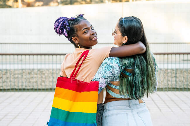 Contenido multiétnico lesbianas novias abrazando en pasarela - foto de stock