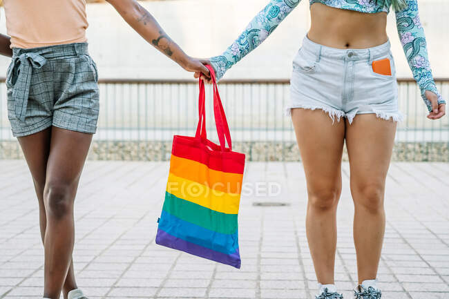 Crop homosexual multiracial couple holding hands on street — Stock Photo