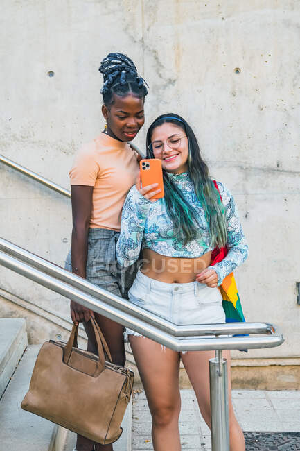Moda multiétnica lesbianas novias tomando selfie en smartphone - foto de stock