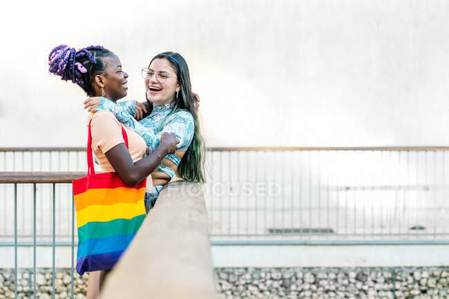Happy homosexual multiracial girlfriends embracing on street — Stock Photo