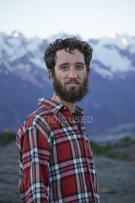 Jeune homme adulte avec chemise bûcheron rouge dans les montagnes — Photo de stock