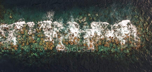 Воздушный вид океанских волн и скал в воде — стоковое фото