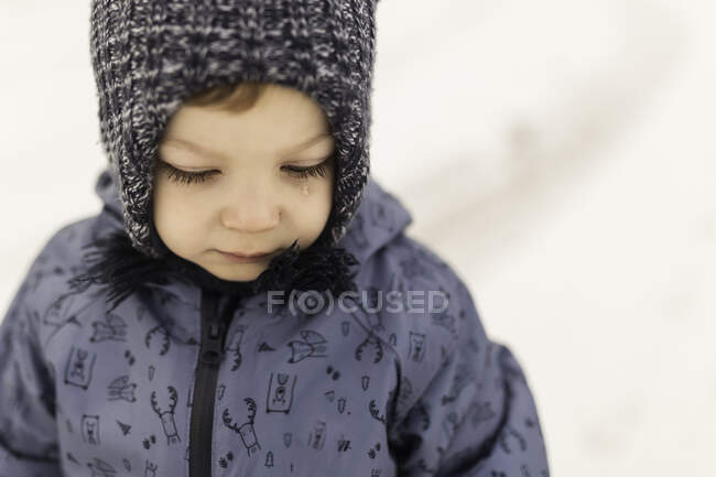 Toddler in winter oneseie and wooly hat with tear — Stock Photo